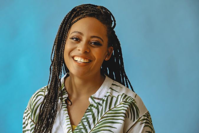 Portrait of confident happy female with long braided hair in printed leaf shirt