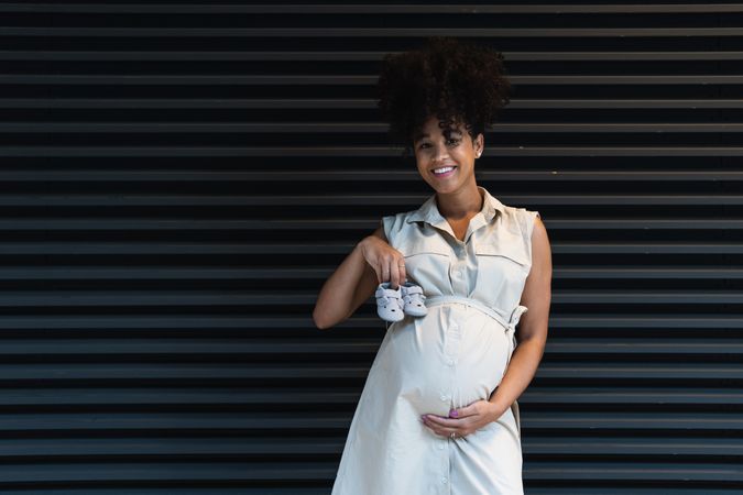 Smiling Black woman showing baby booties to camera