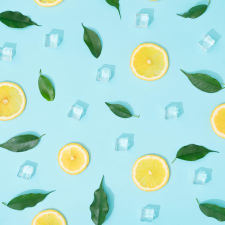 Creative summer background composition with lemon slices, leaves and ice cubes