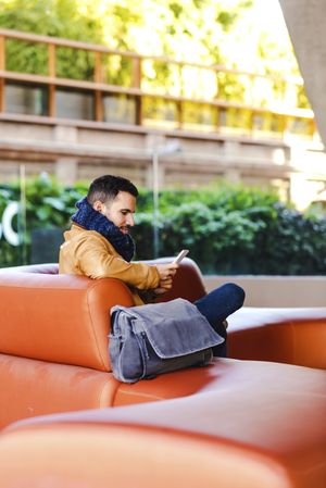 Stylish man using smartphone on couch