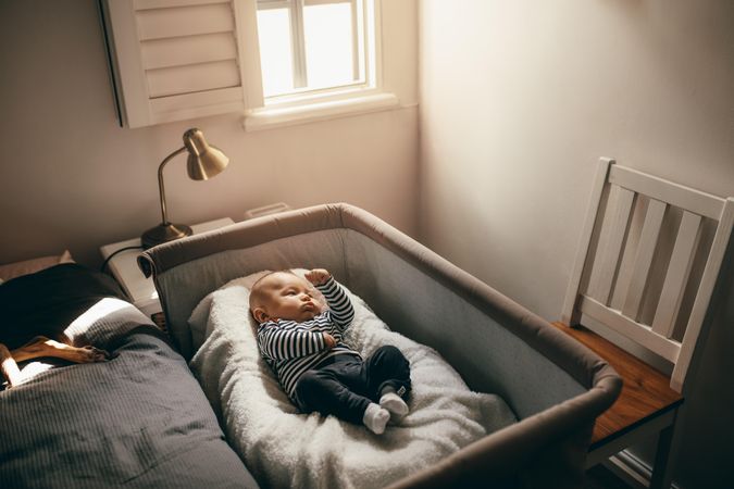 Baby sleeping in a bedside bassinet in bedroom
