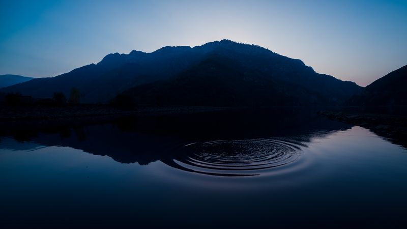 Picturesque view of water surface near amazing rock hills at sunset and blue sky