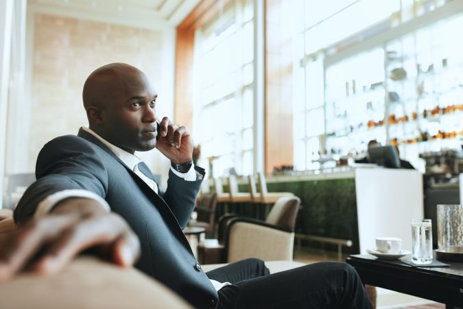 Young business executive using cell phone while waiting at lounge