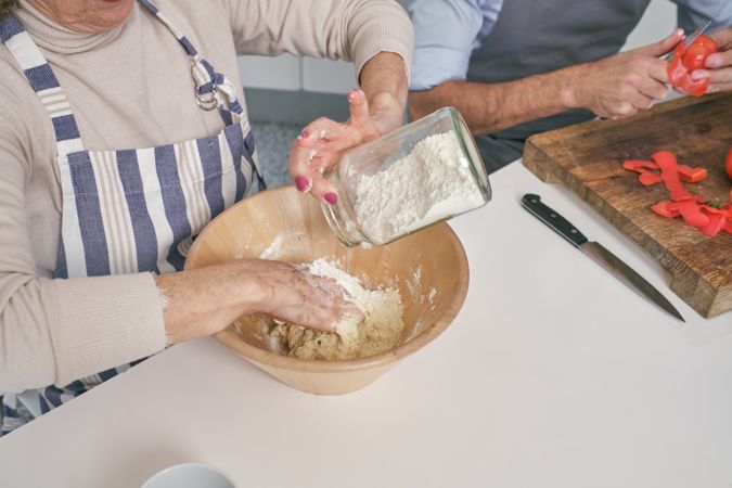 Anonymous woman pouring flour into bowl