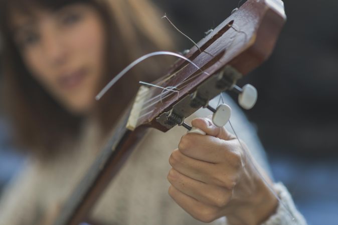 Female hands tuning strings of a guitar