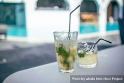 Two cocktails with straws on a table near a pool 42Xje0