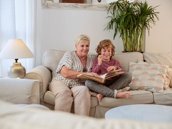 Mature woman with photo album and boy sitting in living room