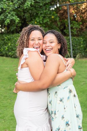 Hispanic mother and teenage daughter hug and smile at the camera