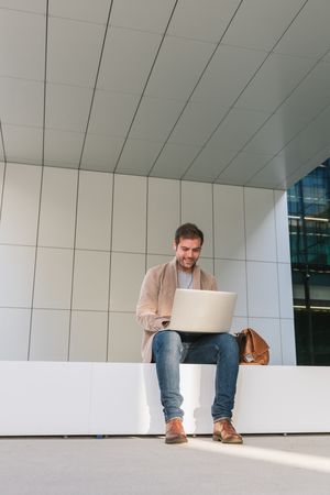 Cheerful businessman using laptop on street