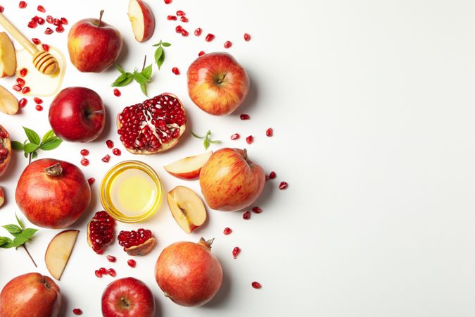 Looking down at fresh apples and pomegranates with honey on side with copy space
