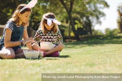 Two girls wearing rabbit ear headband playing in the backyard with baskets 5wP394