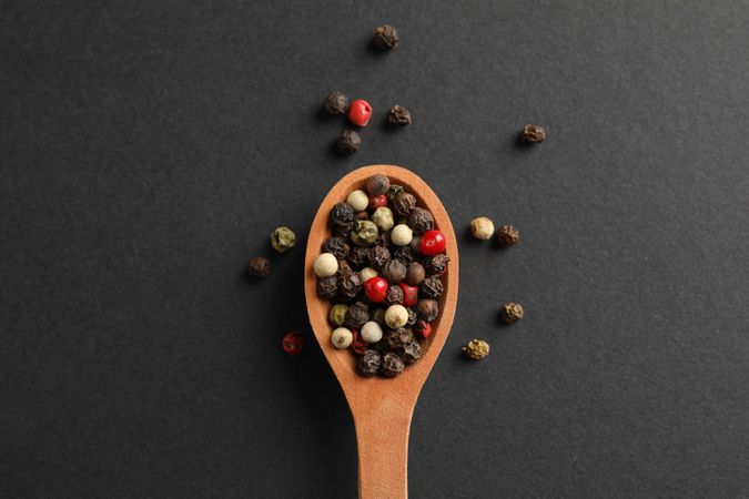 Looking down at wooden spoon of colorful peppercorns, close up