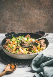 Braised beef stew with potatoes, carrots and parsley, with wooden spoon, copy space