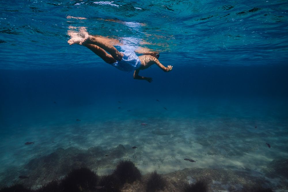 Unrecognizable kid snorkeling in blue sea