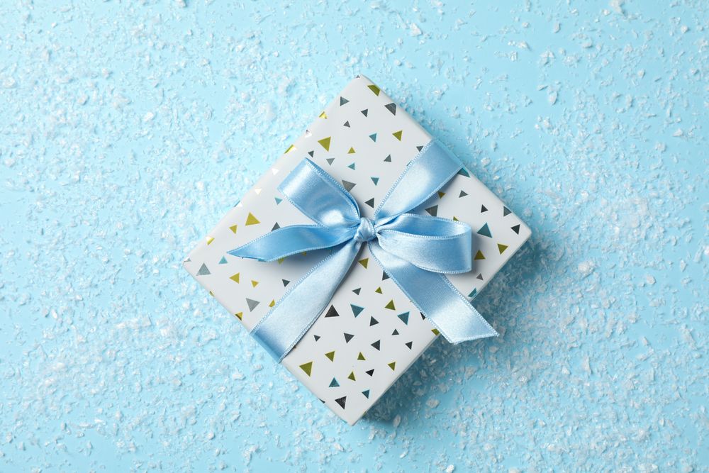 Snow and present with bow on blue background, space for text