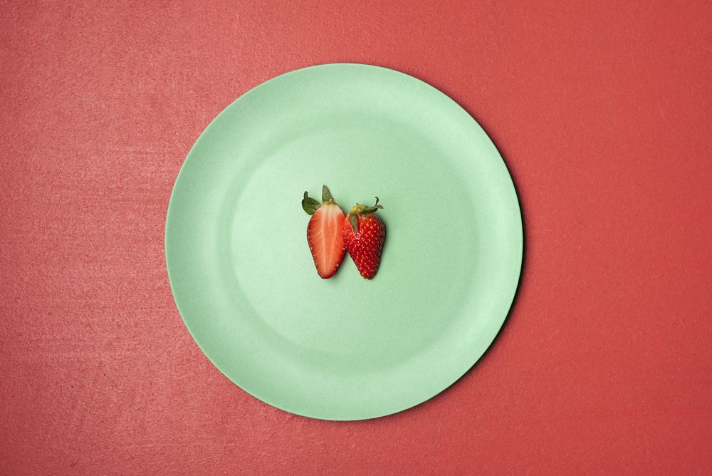 One strawberry cut in half on green plate