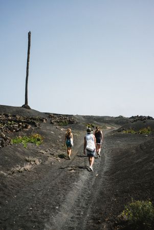 Three friends hiking on dark sand trail in Lanzarote
