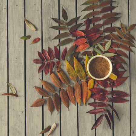 Autumn leaves and coffee cup on wooden table
