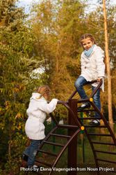 Two young girls climbing playground stairs in park 5zxnQb