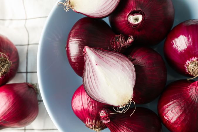 Plate with red onion on towel background, closeup