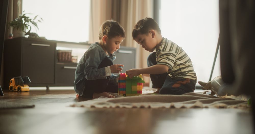 Portrait of Two Male Asian Kids Playing with Colorful Building Blocks in Their Room During the Day.