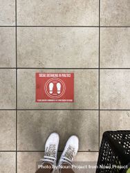 Top view of sign on floor in retail store requesting social distancing 5ngl84