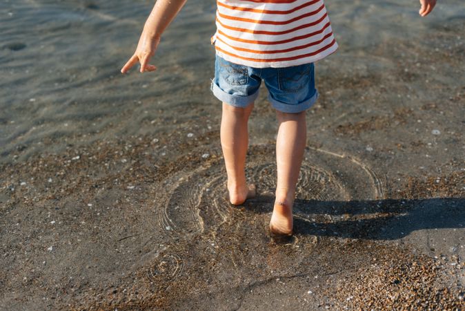 Playful little boy stepping in water