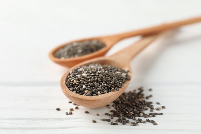 Chia seeds and wooden spoons on wooden background, copy space