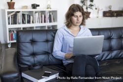 Woman sitting on a sofa at home using a laptop 56GRKd
