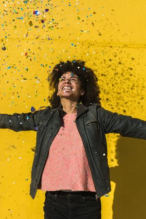 Black woman with afro hair celebrating with confetti.
