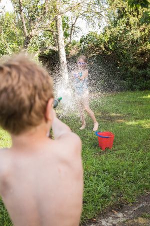 Little kids in swimwear having fun with splashing water
