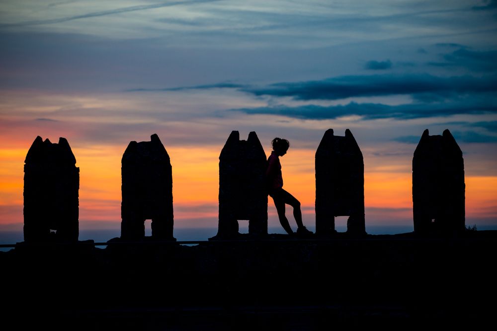 Silhouette of person between stone sculptures in sunset