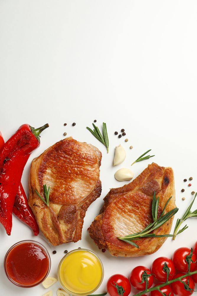 Vegetables and fried steaks on light background, top view