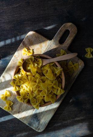 Top view of farfalle pasta in wooden bowl on kitchen counter