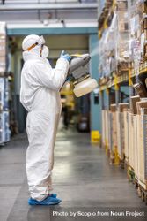 Man in PPE sanitizing shelves in warehouse during lockdown bGGeYb