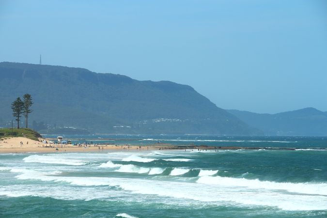 Sandy Beach With Waves Rolling In From The Blue Ocean Under A Clear Blue Sky On A Sunny Day