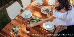 Female setting a dining table outdoors with food and drink 0LenX5