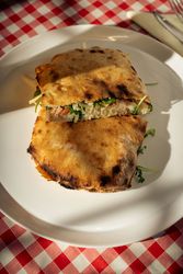 Grilled flatbread sandwich with greens on plate at restaurant