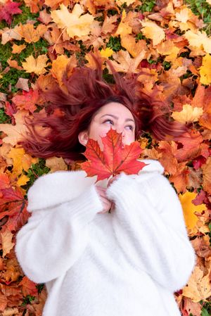 Woman comfortably lying back on colorful autumn leaves