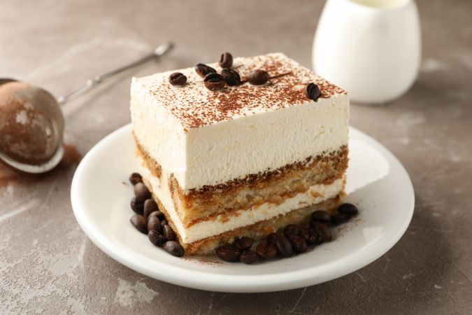 Composition with plate of tiramisu on light brown background. Tasty dessert