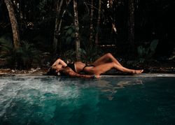 Side view of woman lying back next to beautiful private pool