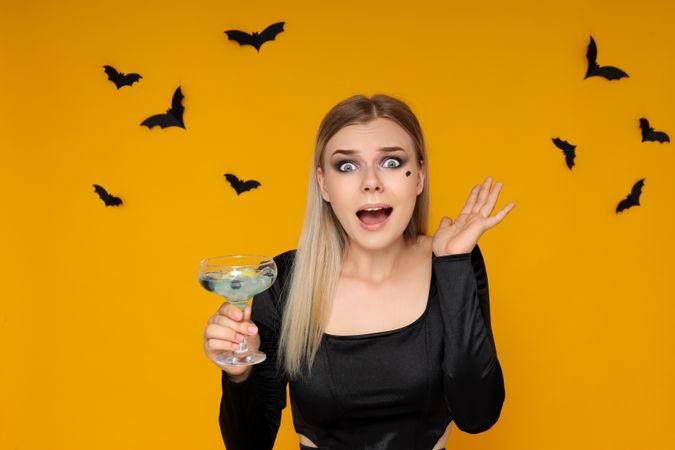 Concept of Halloween, young woman on yellow background