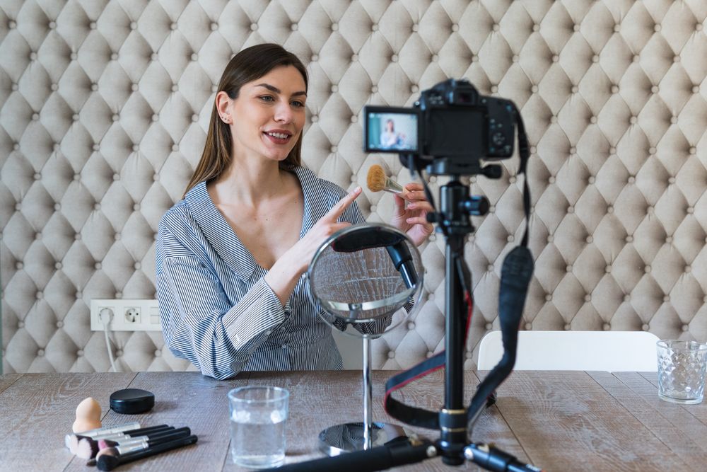 Happy woman applying powder and recording video on camera