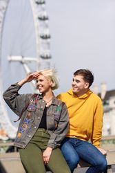 Man and woman friend sitting in front of London Eye