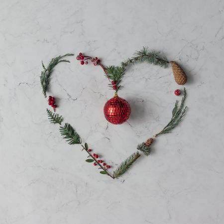 Heart shape made of winter foliage with red disco ball