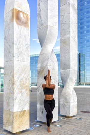 Female balancing on one leg in front of sculpture 