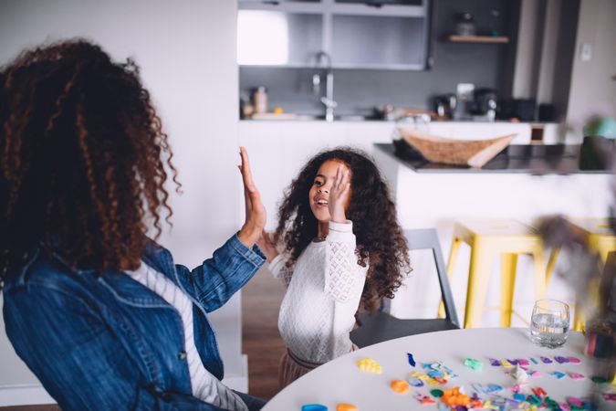 Mother and daughter high five at a kitchen table