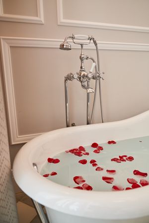 Interior of bathtub full of water and rose petals
