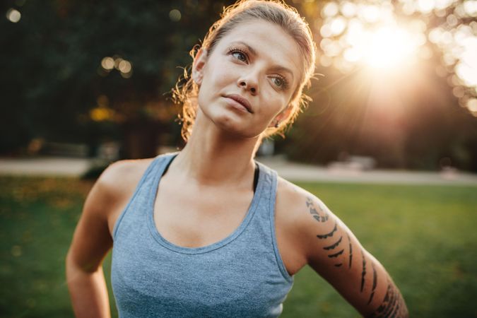 Close up portrait of fit woman standing outdoors and looking away with head tilted