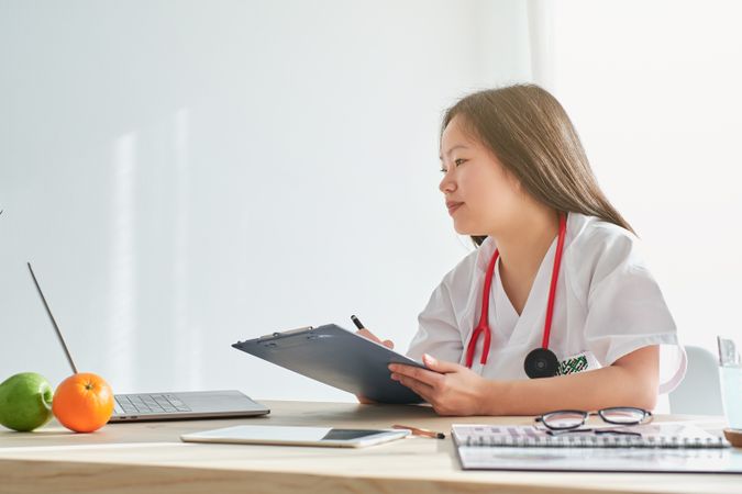 Asian medic with clipboard working in medical office